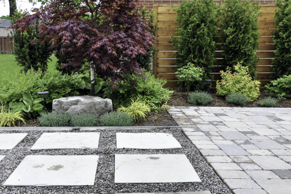 A stone patio featuring a winding stone path surrounded by lush green trees.